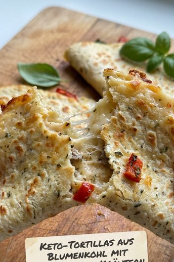 Goldbraune Keto-Tortillas aus Blumenkohl mit mediterranen Kräutern auf einem Holzbrett